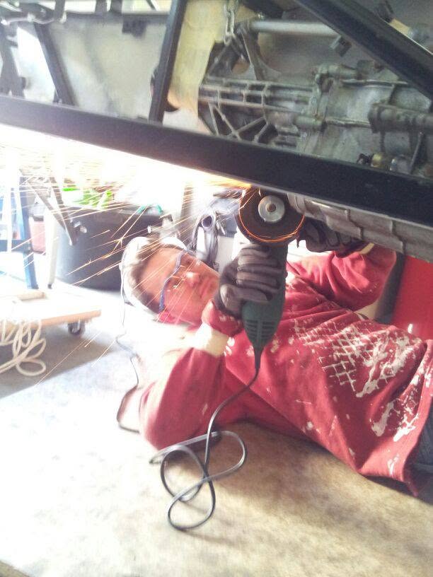 Frank Geiger arbeitet unter einem Fahrzeug mit dem Winkelschleifer